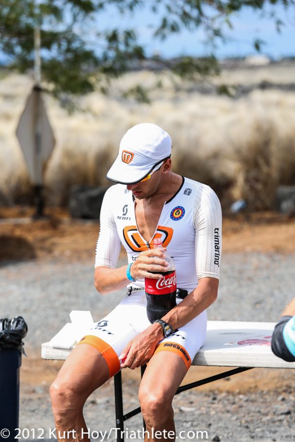 鐵人傳奇名將Marino，在2012年抱著一瓶可樂坐在KONA路跑賽段旁的經典畫面。圖片來源。