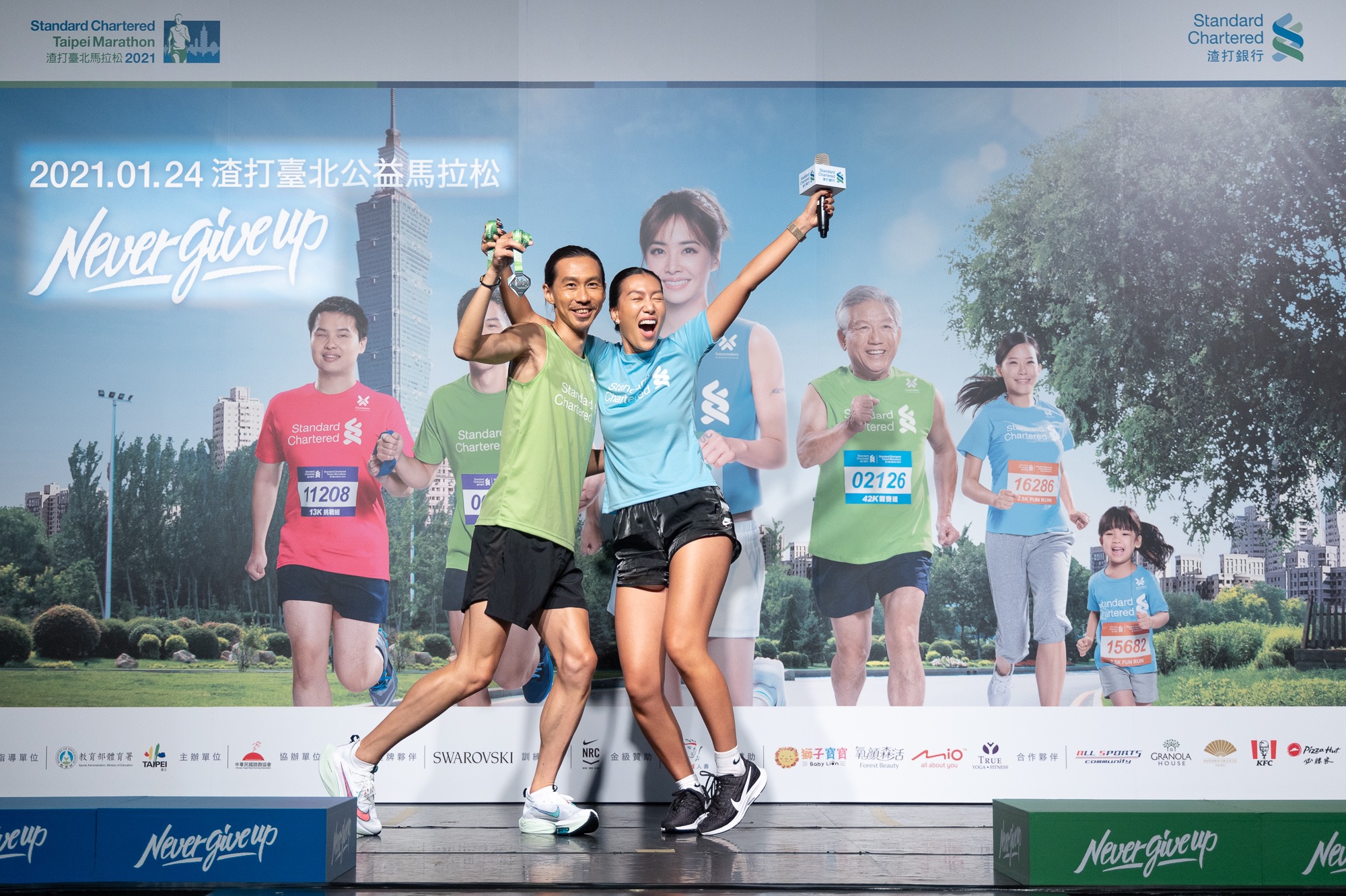 2021渣打臺北公益馬拉松超級戰隊隊長張嘉哲與時尚戰隊隊長莫莉,拿著施華洛世奇獎牌,現場示範完賽時尚照